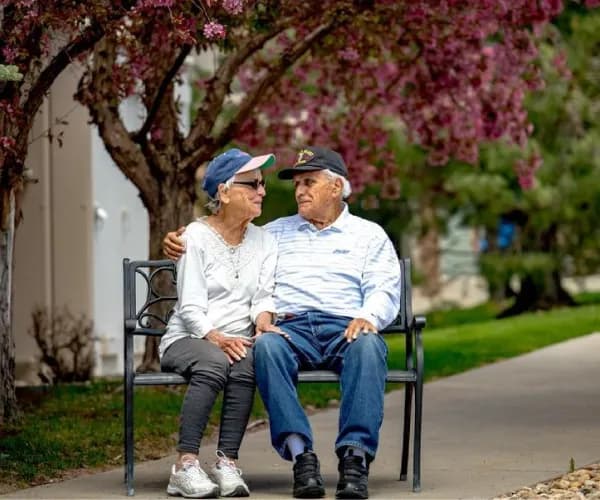 Resident couple enjoying bench in outdoor area