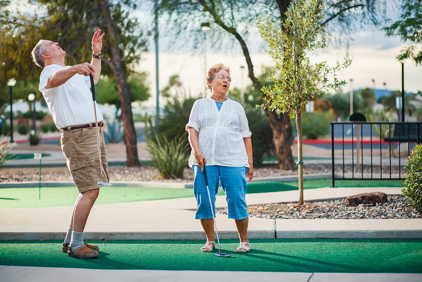 Photo of retired couple having fun playing mini golf.
