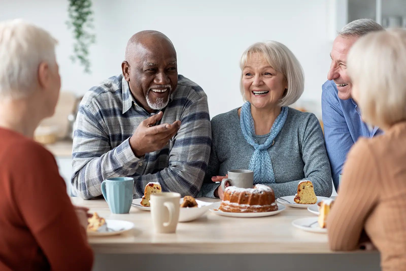 Group of positive elderly people drinking tea with cake