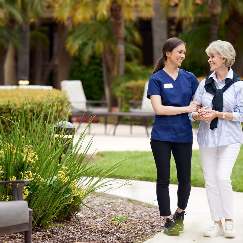 smiing-caregiver-holding-senior-woman-outside