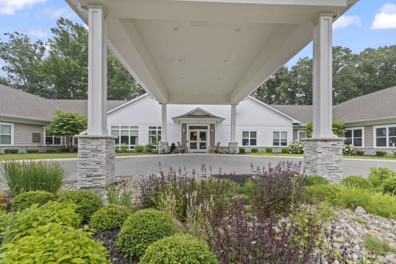 Exterior view of Lakeshore Woods Seniors community entrance with landscaped garden and covered driveway.