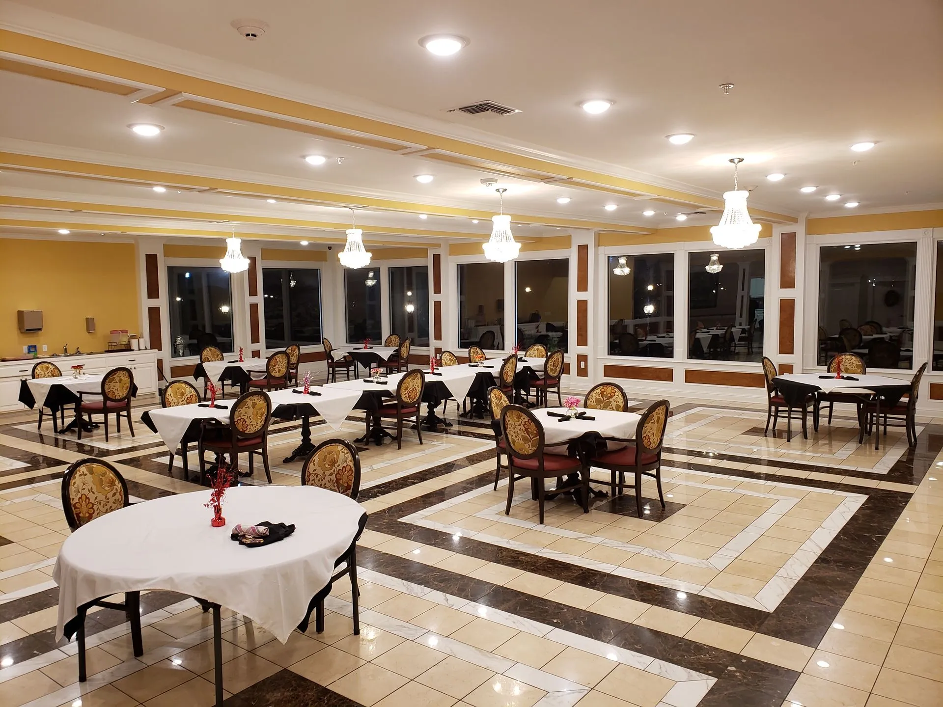 A large dining room with tables and chairs and a tiled floor.