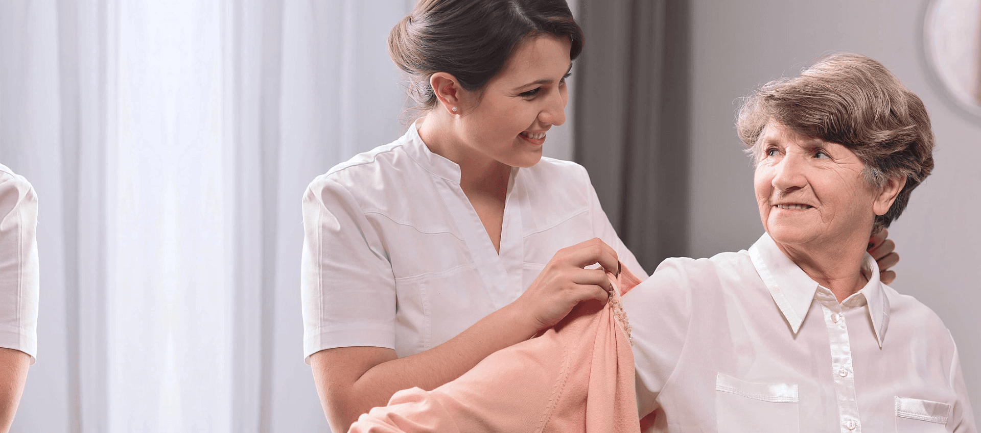 caregiver helping an elderly woman get clothes