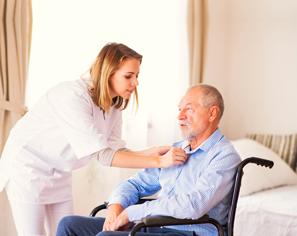 caregiver helping an elder man wear his polo