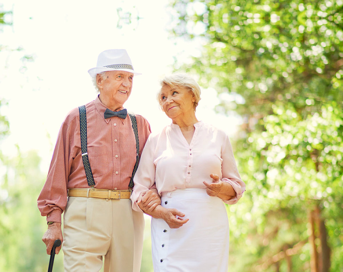 elderly couple walking while holding each other